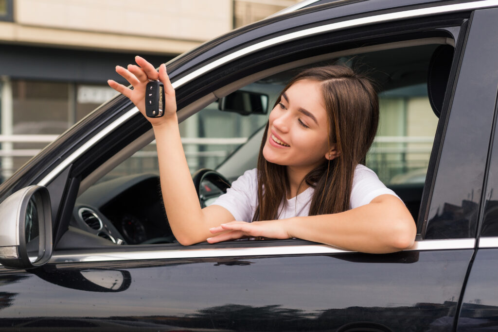 Happy young smiling woman with new car key